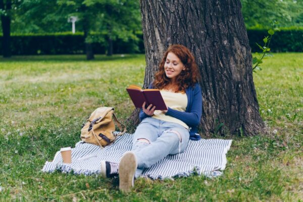 自分時間を楽しむ主婦が外で読書している様子（時間に余裕のある暮らしのイメージ）