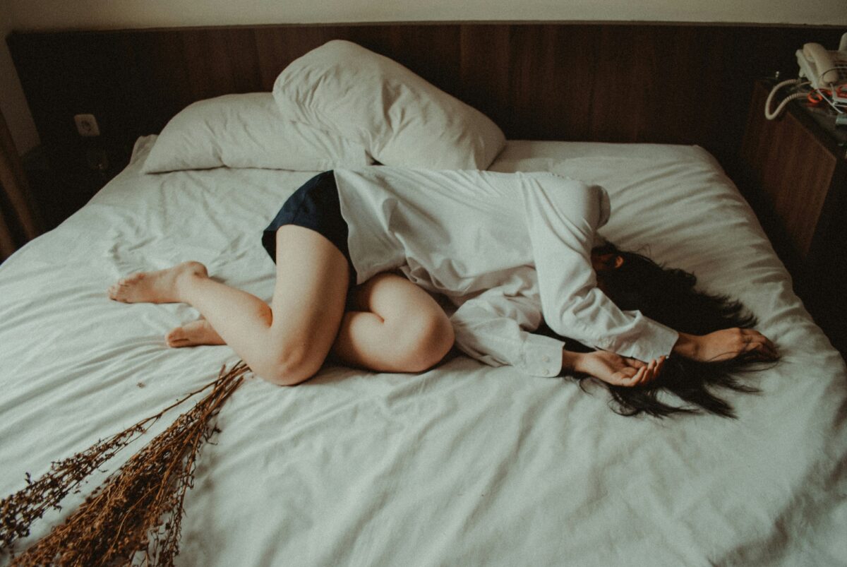 起きたいけれど眠気が残りベッドで休む女性のイメージ